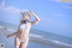 A woman in a white bikini standing on the beach.