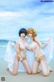 A couple of women in lingerie posing on a beach.