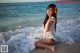 A woman sitting on the beach with a flower in her hair.