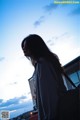 A woman with long black hair standing in front of a building.