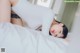 A woman laying on top of a bed in a white shirt.