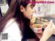 A woman sitting at a table eating food with chopsticks.