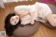 A woman in a white lingerie laying on a brown pillow.