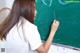 A young woman writing on a blackboard with chalk.