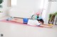 A woman laying on a pink yoga mat with a yellow ball.