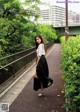 A woman in a white shirt and black skirt walking down a sidewalk.