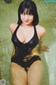 A woman in a black bathing suit sitting in a pool.