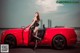 A woman sitting in the driver's seat of a red sports car.