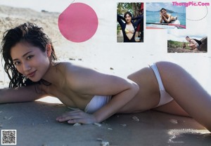 A woman in a white bikini laying on the beach.