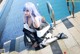 A woman with long blue hair sitting next to a swimming pool.