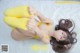 A woman in a yellow bikini laying on a white blanket.